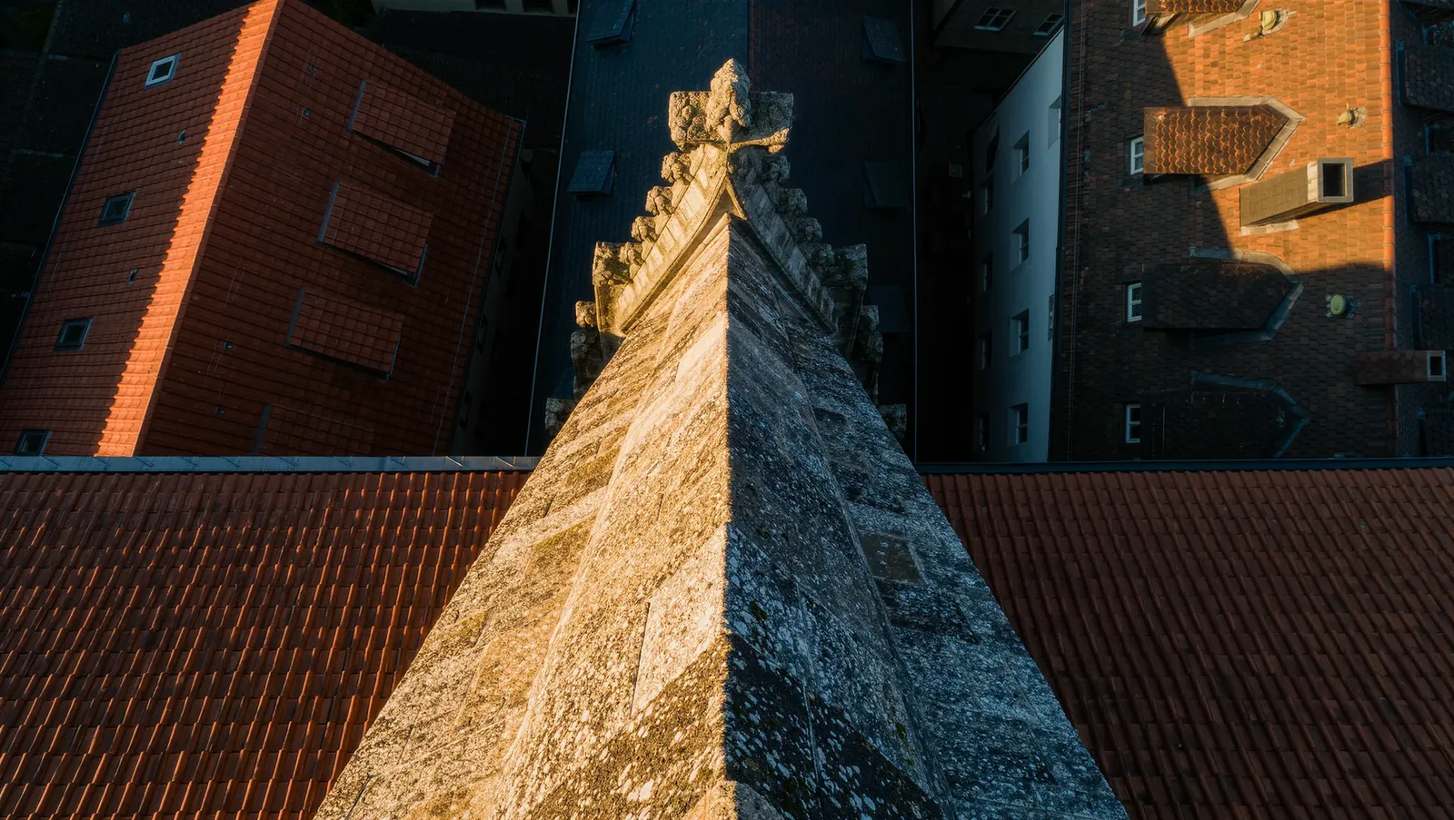 Symbolbild Kirchturm über Ziegeldächern