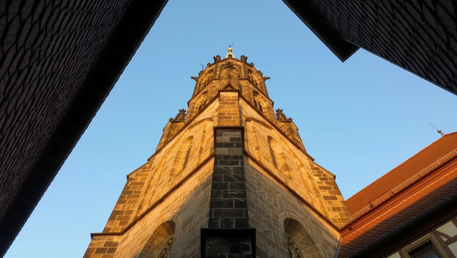 Symbolbild Kirchturm über Ziegeldächern