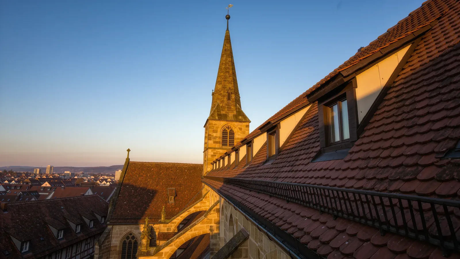 Symbolbild Kirchturm über Ziegeldächern